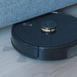 Black robot vacuum cleaning a hardwood floor