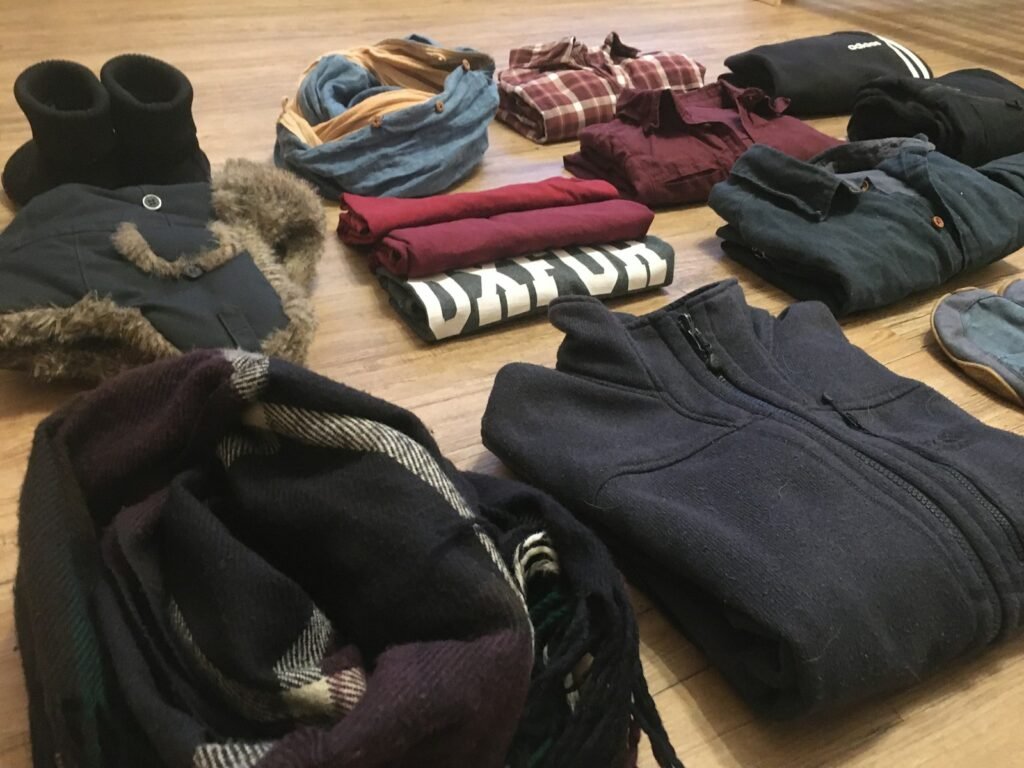 A curated pile of neutral-toned clothing including a sweater and shoes