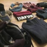 A curated pile of neutral-toned clothing including a sweater and shoes